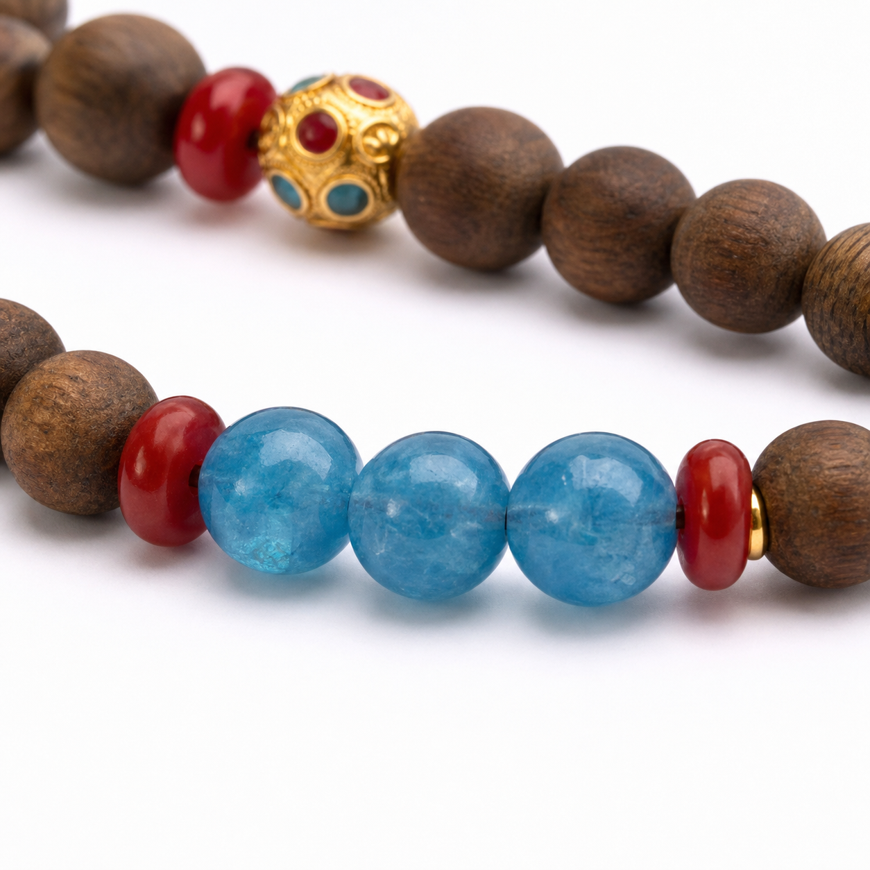 Close-up of agarwood grain, three blue beads, red spacers, and gold filigree bead
